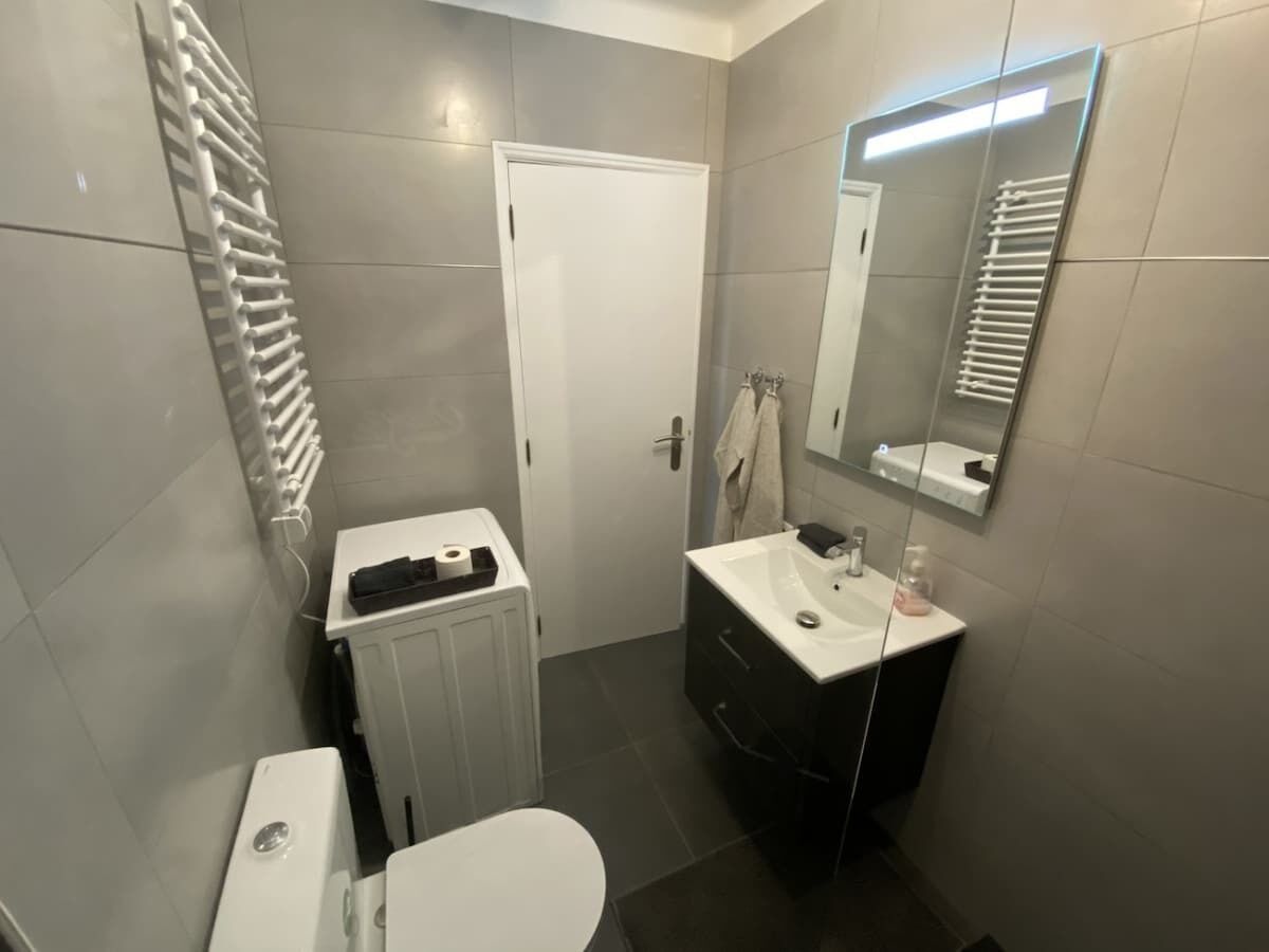 Een badkamer met toilet, wastafel, spiegel en handdoekhouder.