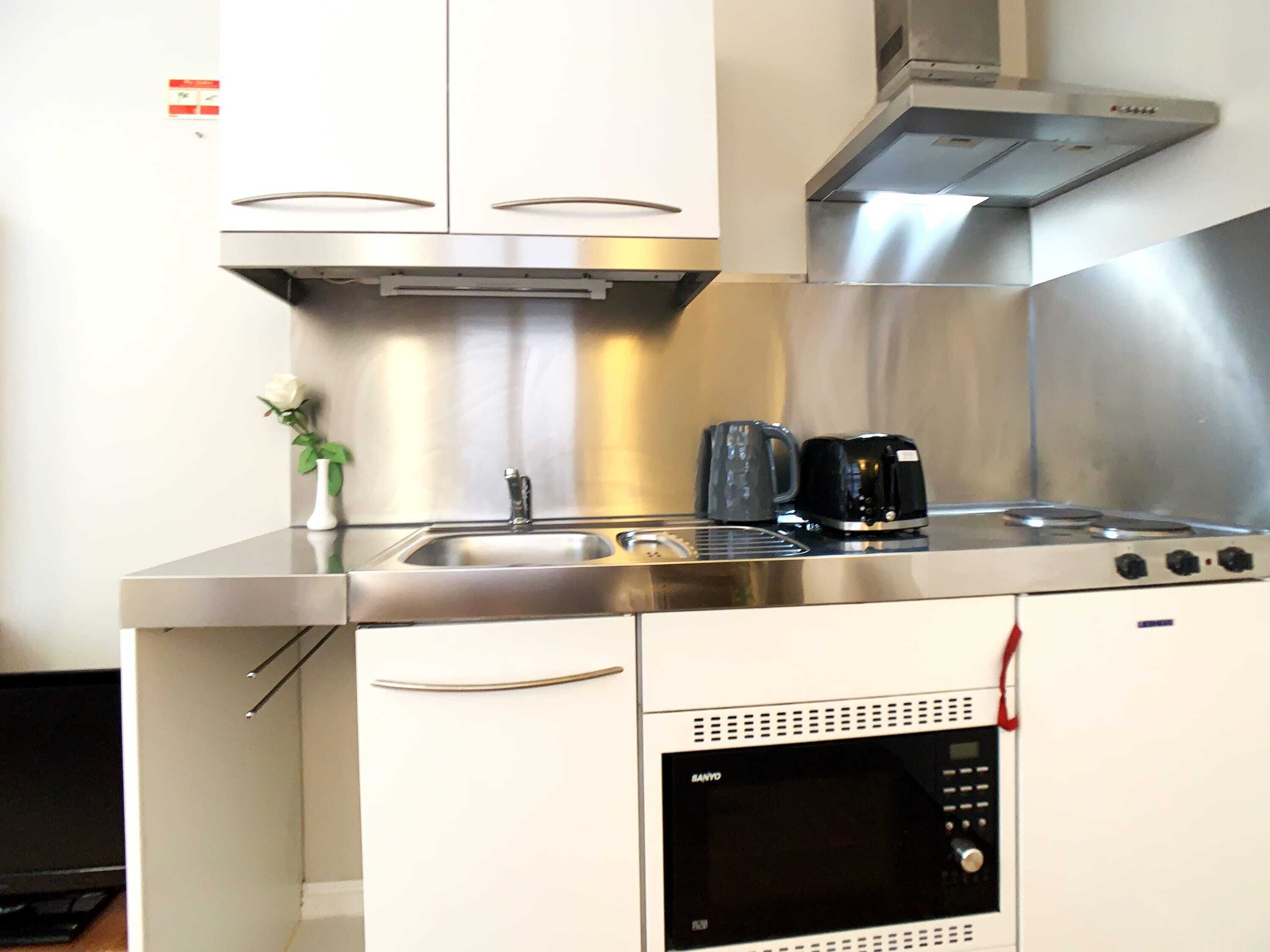 A compact kitchen with a stainless steel stove, a microwave, and a coffee maker.