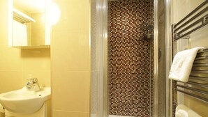 Une salle de bain avec un lavabo, une douche avec un mur carrelé et un porte-serviettes.
