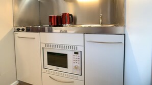 Eine kompakte Küchenzeile mit Mikrowelle, kleinem Backofen und Wasserkocher.