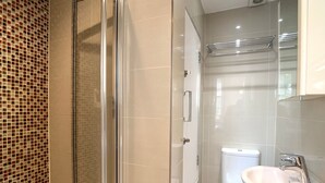 Een moderne badkamer met een douchecabine van glas, een wit toilet en een wastafel met een spiegel erboven.