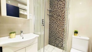 A modern bathroom with a glass-enclosed shower, a white sink, and a toilet. - S5 - Cute Apartment with Balcony by Oxford Street (London)