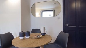 Une pièce avec une table ronde en bois, deux chaises, une lampe et une porte sombre.