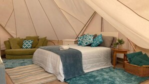 Eine Zelthütte mit einem Bett, einer Couch, einem kleinen Tisch und einem Korb.