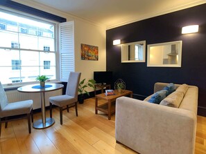 Una sala de estar moderna con un sofá, sillas, una mesa de centro y un televisor.