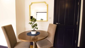 Una mesa redonda con dos sillas, una planta en maceta y un espejo en la pared.