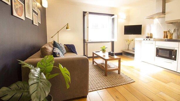 Una sala de estar moderna con sofá, mesa de centro y vista a la cocina.