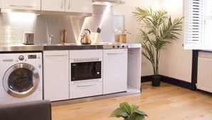 A compact kitchen with a washing machine, oven, and a stove.