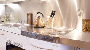 A modern kitchen with stainless steel appliances, a kettle, and a knife holder.