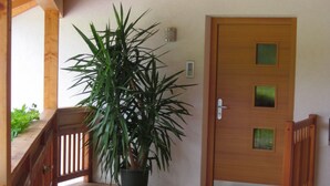 A wooden porch with a potted plant, a wooden door with a window, and a wooden railing. - Ferienwohnung mit Schwimmbad (Schabs)