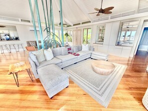 A spacious living room with a sectional sofa, a coffee table, and a dining area with bar stools.
