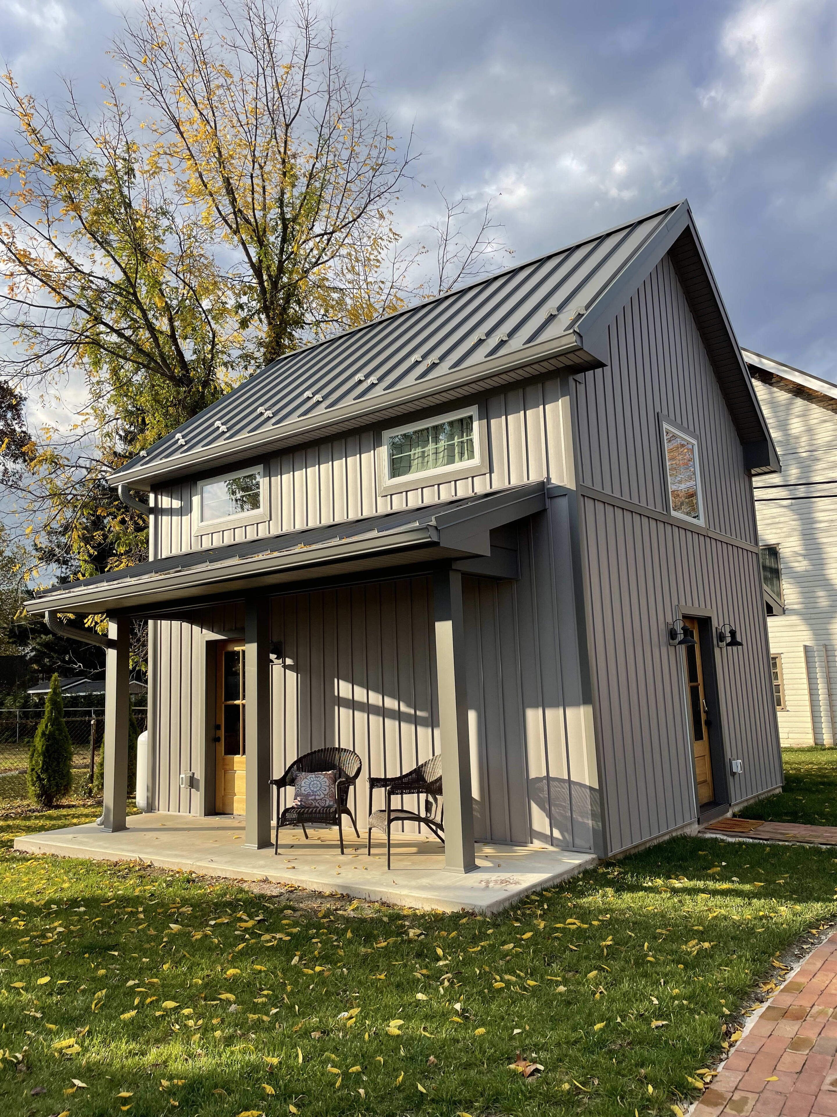 A two-story house with a covered porch, a small front door, and a window.