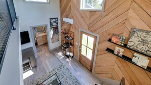 Une chambre moderne de style loft, dotée d’un parquet en bois à motifs en chevrons, d’une bibliothèque intégrée et d’une grande fenêtre laissant entrer la lumière naturelle.