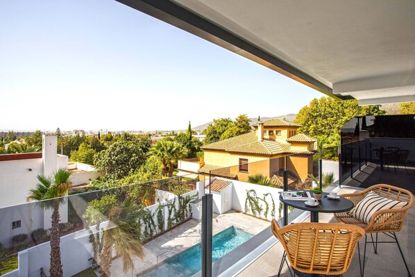 A balcony with a pool, wicker chairs, and a table with cups. - Genteel Home Arruzafa VIII (Cordoba)