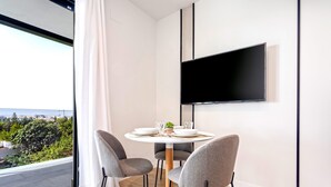 A modern dining area with a round table, grey chairs, and a flat-screen TV mounted on the wall. - Genteel Home Arruzafa VIII (Cordoba)