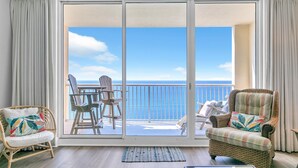 Un balcon avec vue sur l’océan, des fauteuils en osier, une table et un fauteuil rembourré.