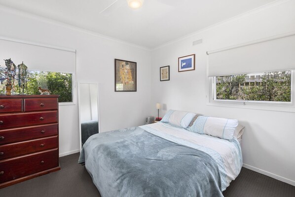 A bedroom with a bed, dresser, and window.
