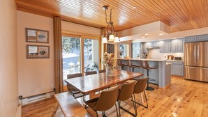 Une cuisine moderne avec un plancher en bois, un coin repas avec une table et des chaises en bois, et une vue sur l’extérieur.