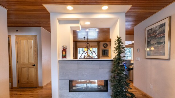 Un intérieur moderne avec une cheminée, un plancher en bois et un sapin de Noël.