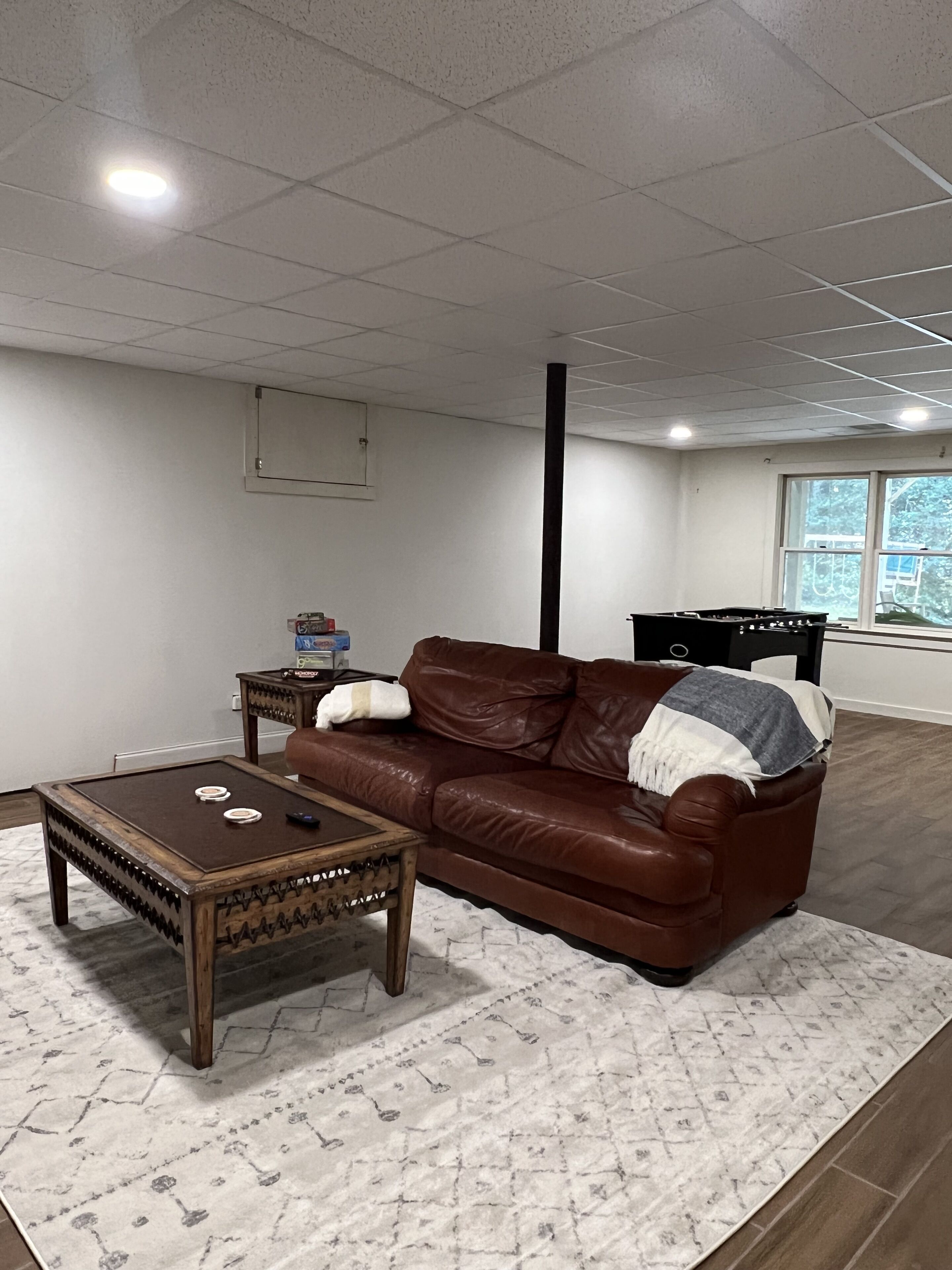 Ein möbliertes Wohnzimmer mit einer braunen Ledersofa, einem Holztisch und einem gemusterten Teppich.
