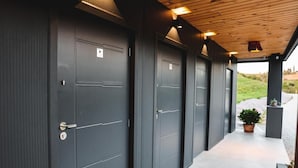 A row of dark grey doors with a modern design, a wooden ceiling, and a potted plant on the right. - Tends Resort Posestvo SONČNI RAJ (Maribor)