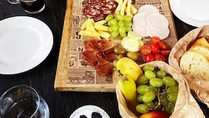 A table set with a variety of food items including cheese, grapes, and bread, along with several glasses and bottles. - Tends Resort Posestvo SONČNI RAJ (Maribor)