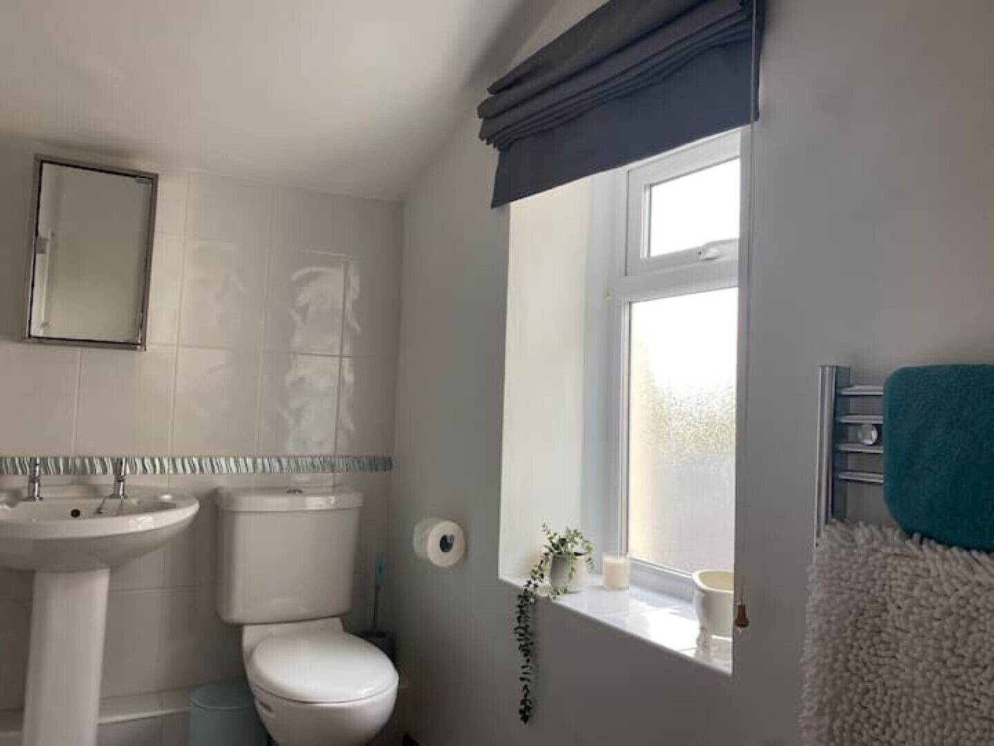 A bathroom with a sink, toilet, and window.