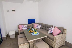 A corner seating area with a sofa, a small table, and a side table. - Casa Gecko | Rubicon Retreat by Villas Now (Playa Blanca)