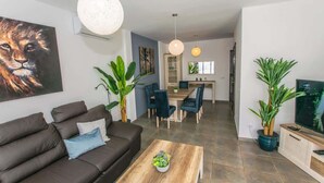 Een moderne woonkamer met een bank, salontafel en een eethoek.