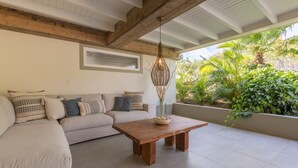 Un salon moderne avec une table basse en bois, un canapé beige et un plafond avec des poutres apparentes.