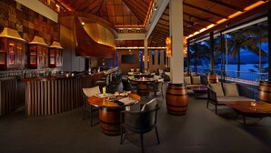 A restaurant with a bar area, outdoor seating, and a view of the ocean. - Taj Wayanad Resort & Spa, Kerala (Vythiri)