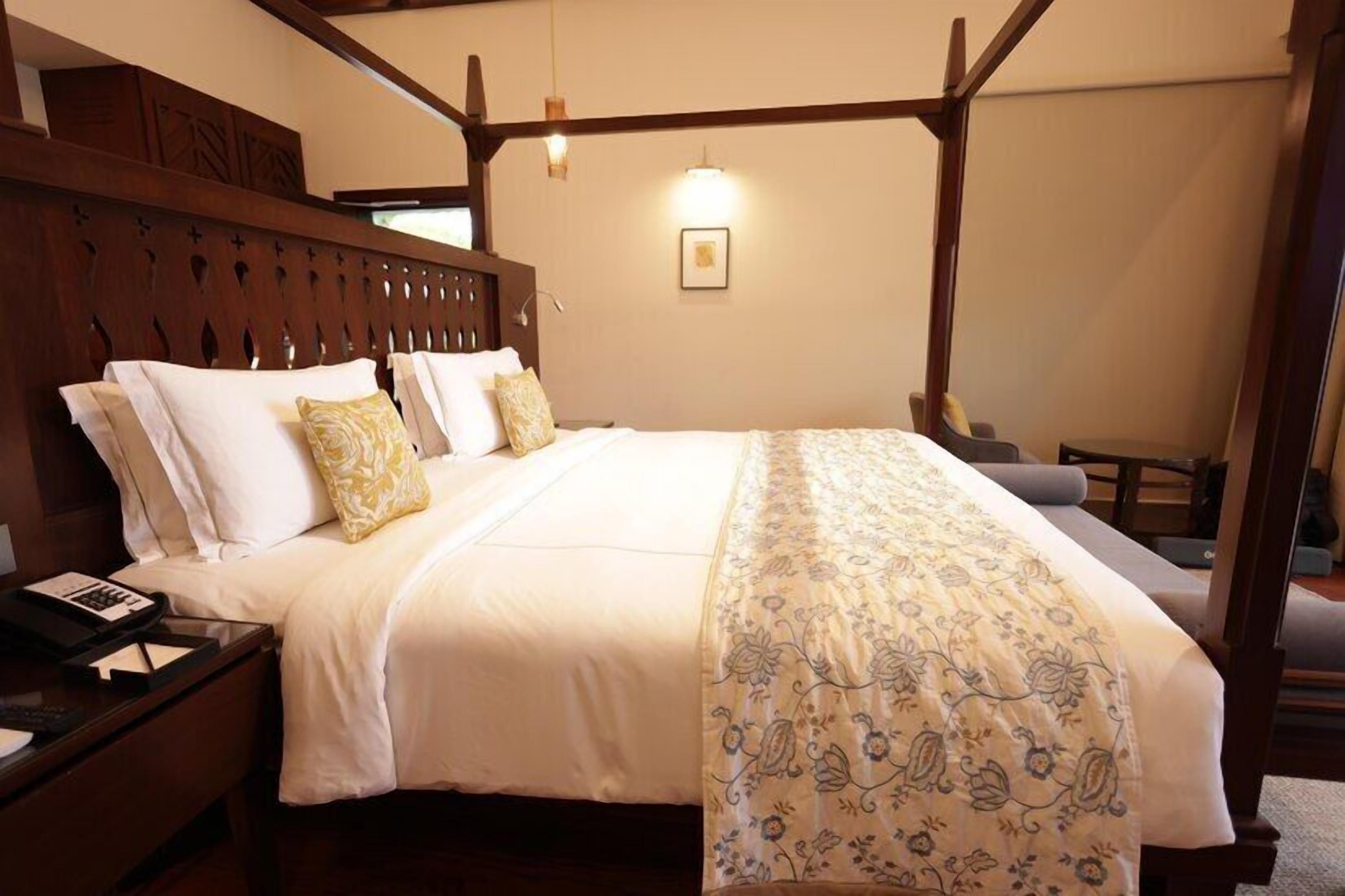 A spacious bedroom with a large bed, wooden headboard, and a bedside table with a lamp.