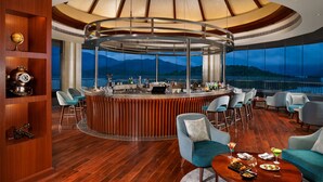 A bar area with a circular bar, seating, and a view of mountains. - Taj Wayanad Resort & Spa, Kerala (Vythiri)