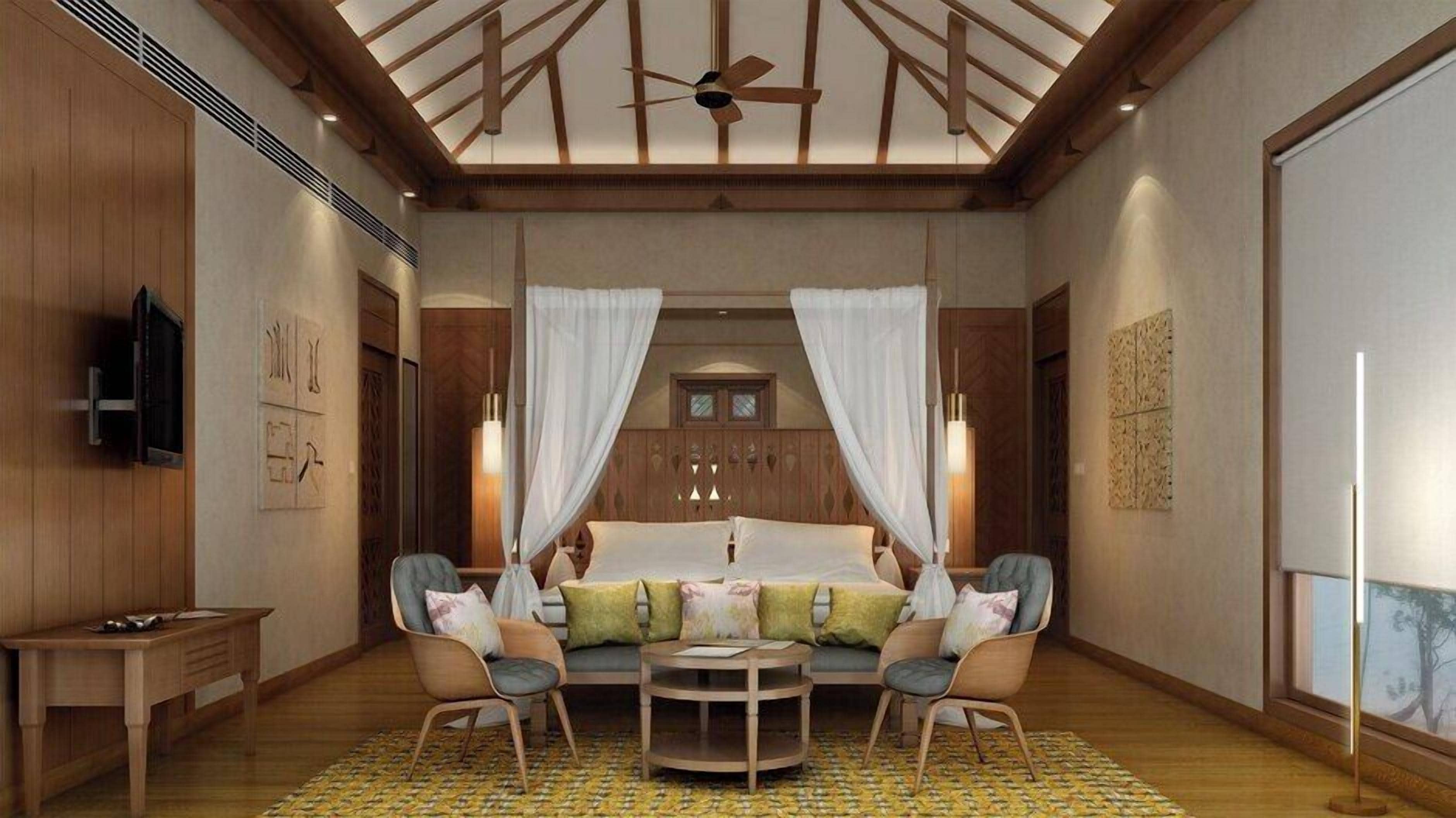 A spacious bedroom with a large bed, two chairs, a small table, and a ceiling fan.