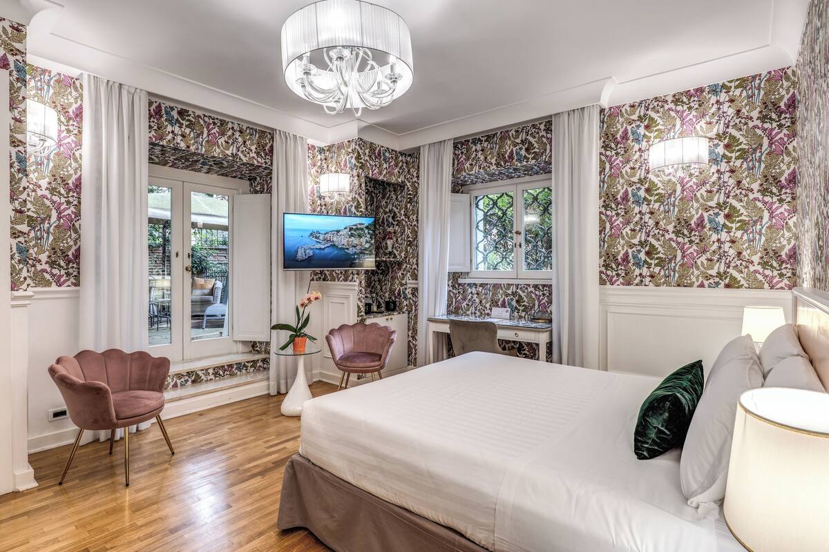 A bedroom with a large bed, a desk, a television, and a chair.