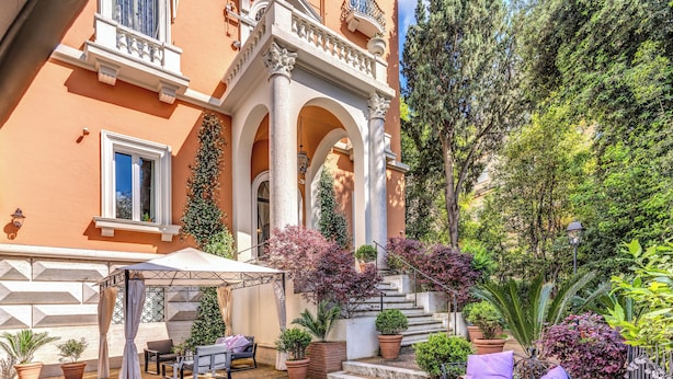 A courtyard with a covered seating area, potted plants, and a staircase leading to an upper level. - Mangili Garden Hotel (Rome)