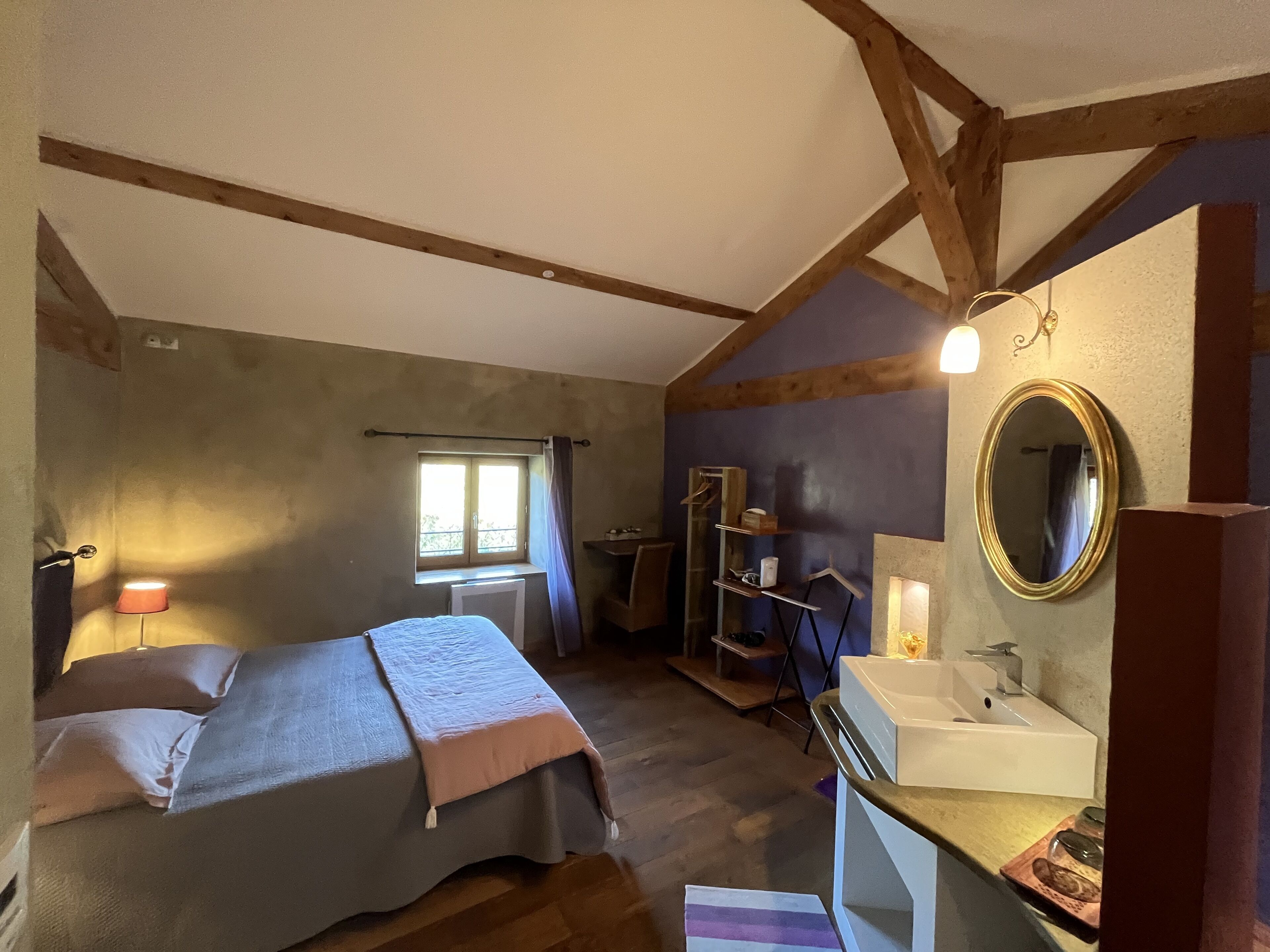 A bedroom with a bed, a window, a dresser, a mirror, and a sink.