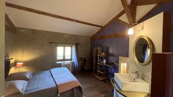 A bedroom with a bed, a window, a dresser, a mirror, and a sink.