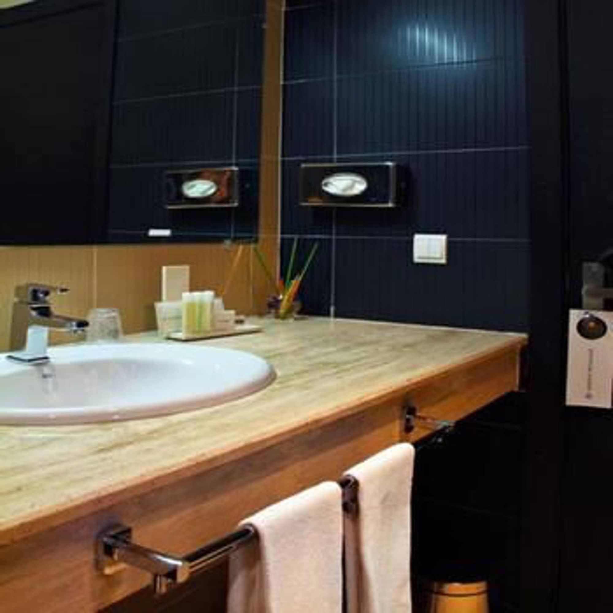 Une salle de bain avec un meuble-lavabo en bois, un lavabo blanc et un miroir.