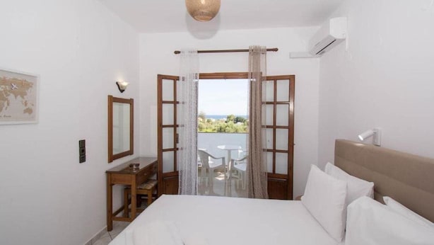 Une chambre d’hôtel avec un lit, un bureau, une chaise, une carte accrochée au mur et une vue sur l’extérieur.