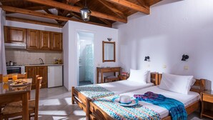 Une pièce comprenant un lit, des tables de chevet, un bureau, une chaise, un petit coin cuisine et une salle de bain.