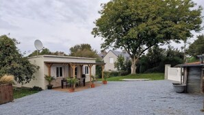 A covered outdoor seating area with a gravel driveway leading to a house. - Small cottage (Tourville-sur-Sienne)