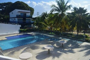 Relax by the pool surrounded by a deck and lounge chairs, with a view of a nearby building and palm trees.