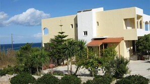 A modern two-story building with a flat roof and a balcony, surrounded by greenery and a clear sky. - Babis Hotel (Rethymno)