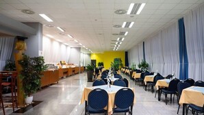 A spacious dining area with tables and chairs, a reception desk, and potted plants. - Olympik Artemis Hotel (Prague)