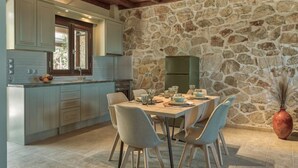 Une cuisine moderne avec des meubles de couleur bleu clair, un mur en pierre et un coin repas avec une table dressée pour quatre personnes.