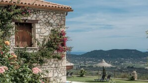Un bâtiment en pierre avec une porte en bois, entouré d’une végétation luxuriante et de fleurs roses.