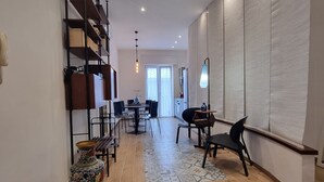 A modern living room with a wooden floor, a dining area with a table and chairs, and a kitchen area with cabinets and a countertop. - G & G NAPOLI (Naples)
