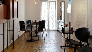 A modern kitchen with a dining area, wooden flooring, and a patterned rug. - G & G NAPOLI (Naples)