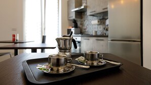 A kitchen with a coffee maker, two cups, and a tray on a wooden table. - G & G NAPOLI (Naples)